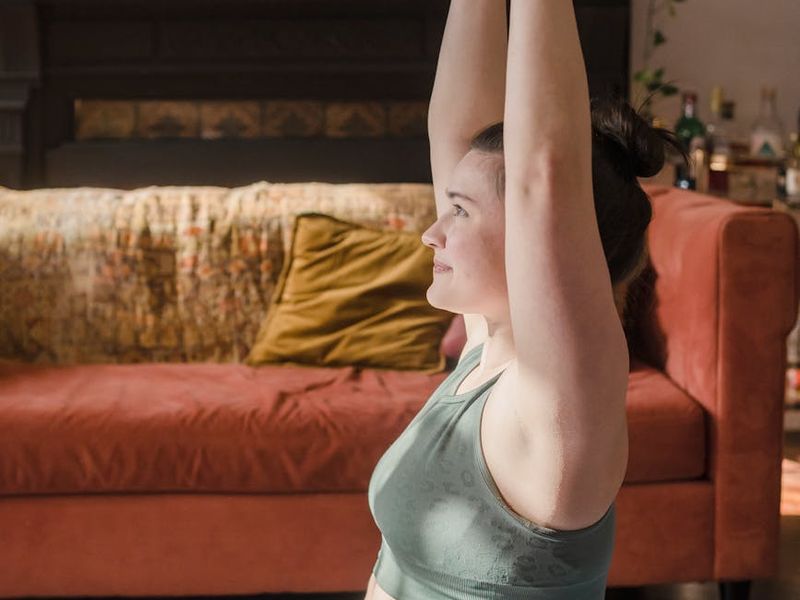 Person focused during a stretching exercise in a calm setting.
