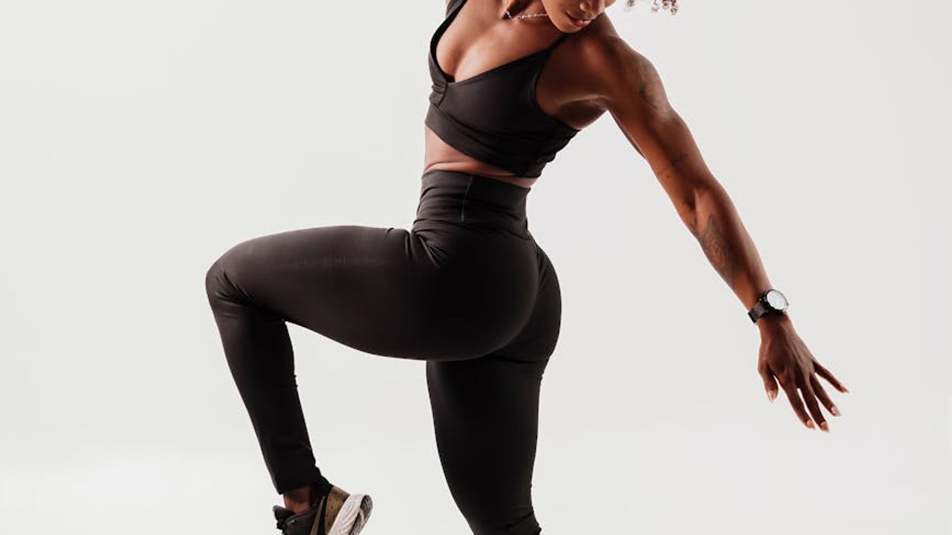 Person in a dynamic cardio pose in a minimalist studio.