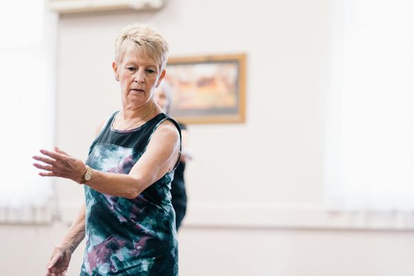 Woman performing a fluid motion exercise in a bright room.